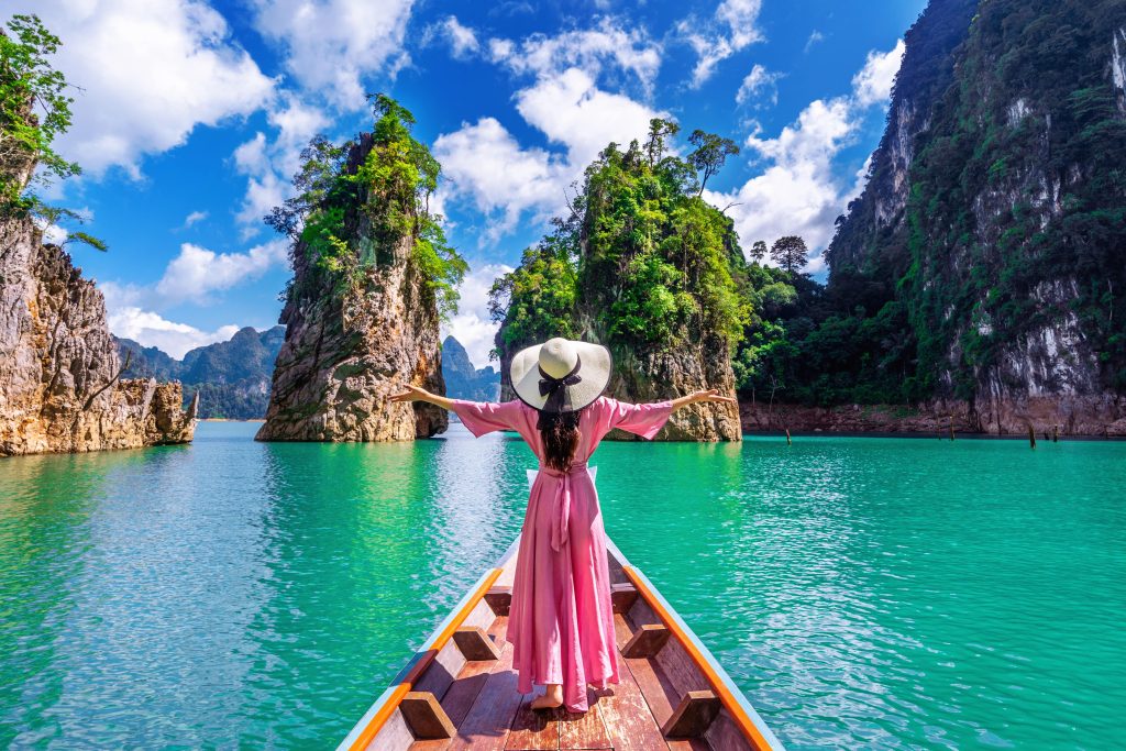 beautiful-girl-standing-boat-looking-mountains-ratchaprapha-dam-khao-sok-national-park-surat-thani-province-thailand-min